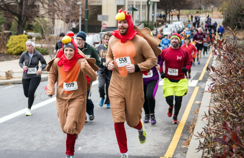 People gleefully running in turkey costumes at a turkey trot event for charity